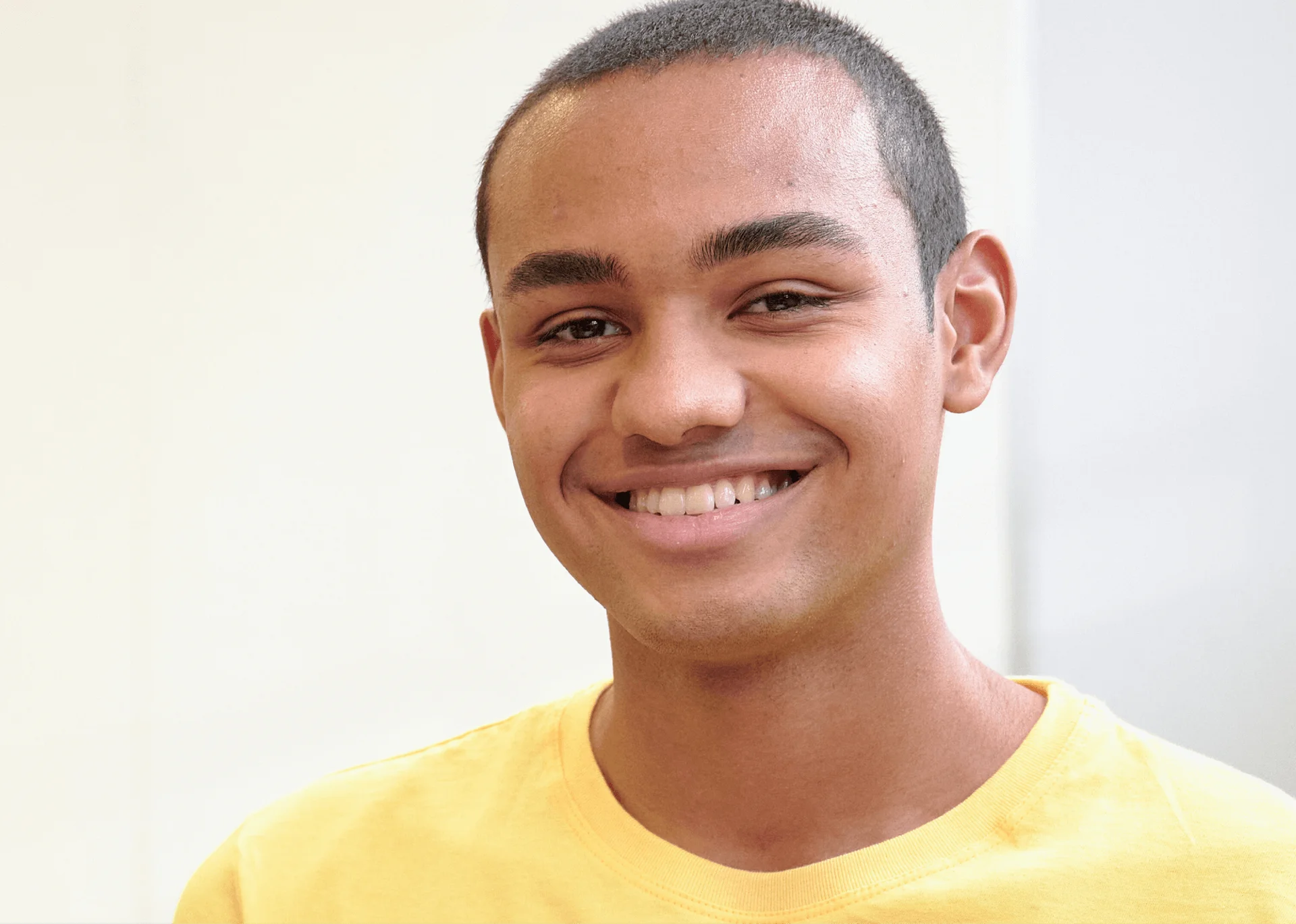 Smiling young man in a yellow shirt showing straight teeth