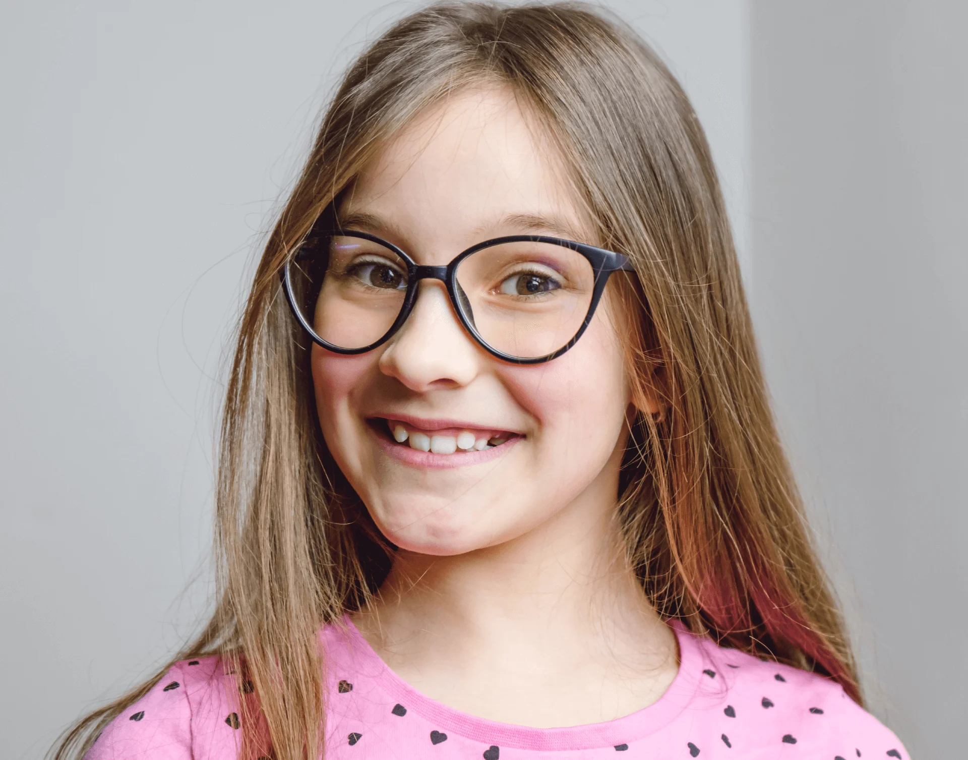 Smiling young girl with glasses showing her teeth