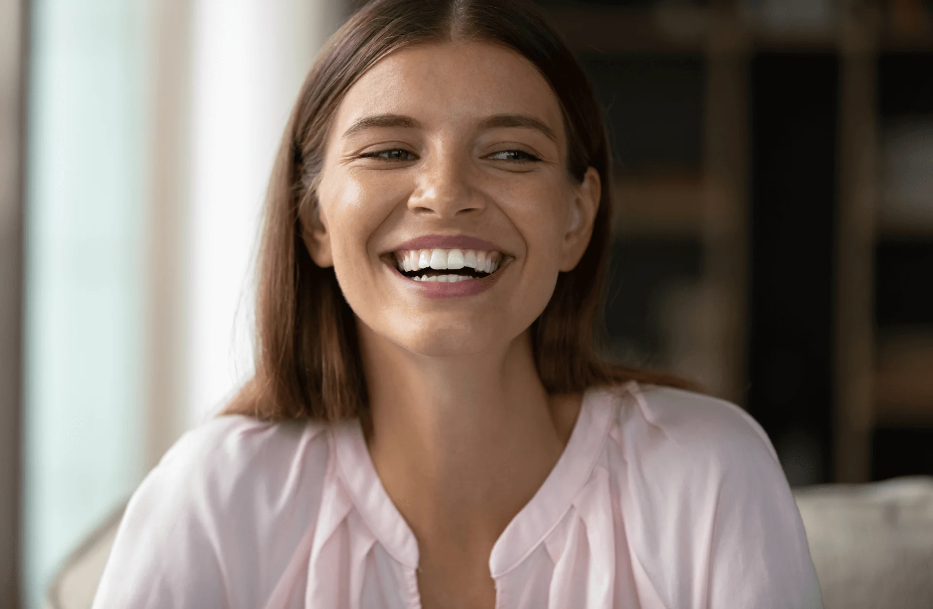 Smiling teen girl with straight white teeth wearing a soft pink blouse