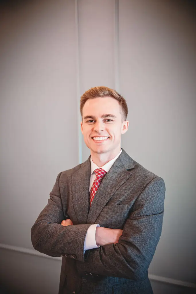 Smiling man in a gray suit and red tie with arms crossed